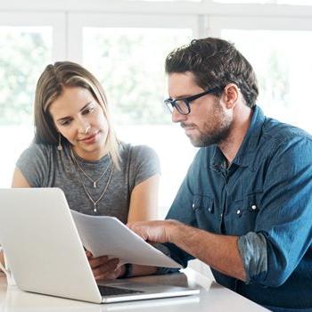 A couple reviews their college savings accounts in front of a computer.